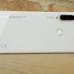 Biały smartfon Huawei MAR-LX1A z potrójnym aparatem i czytnikiem linii papilarnych na drewnianym blacie.
