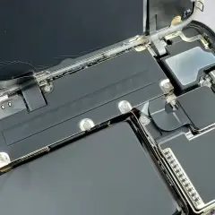 Naprawa telefonu z powodu słabej baterii w telefonie. Wkrętak odkręca śrubkę przy baterii.