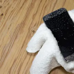 Telefon Samsung z kroplami wody na ekranie, owinięty w biały ręcznik. Jak wyłączyć czujnik wilgoci Samsung, gdy telefon jest mokry?