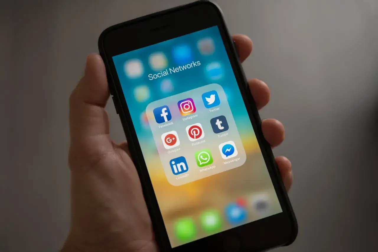Dłoń trzyma smartfon z ikonami mediów społecznościowych. Czy 10 GB internetu to dużo na te wszystkie aplikacje?