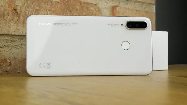 Biały smartfon Huawei MAR-LX1A z potrójnym aparatem i czytnikiem linii papilarnych na drewnianym blacie.