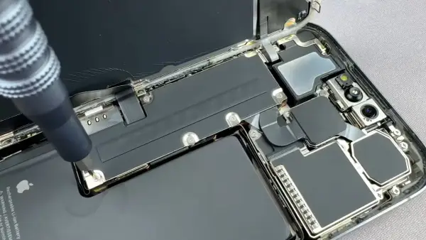 Naprawa telefonu z powodu słabej baterii w telefonie. Wkrętak odkręca śrubkę przy baterii.