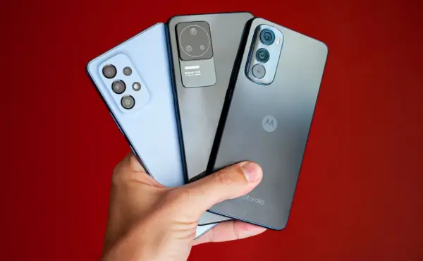Dłoń trzyma trzy smartfony: jasnoniebieski, szary i ciemnoszary z logo Motorola. Kraj pochodzenia tej marki to USA.